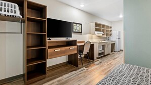 Una cocina moderna con armarios de madera, un televisor integrado y un refrigerador.