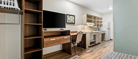 A modern kitchen with wooden cabinets, a built-in TV, and a refrigerator.