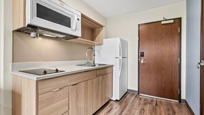 Una cocina compacta equipada con microondas, lavamanos y refrigerador.