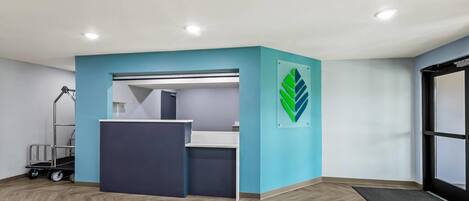 A modern office space with a blue accent wall, a desk area, and a wooden herringbone floor.