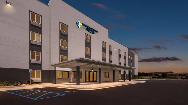 Un hotel moderno con fachada plana, múltiples ventanas y un acceso cubierto.
