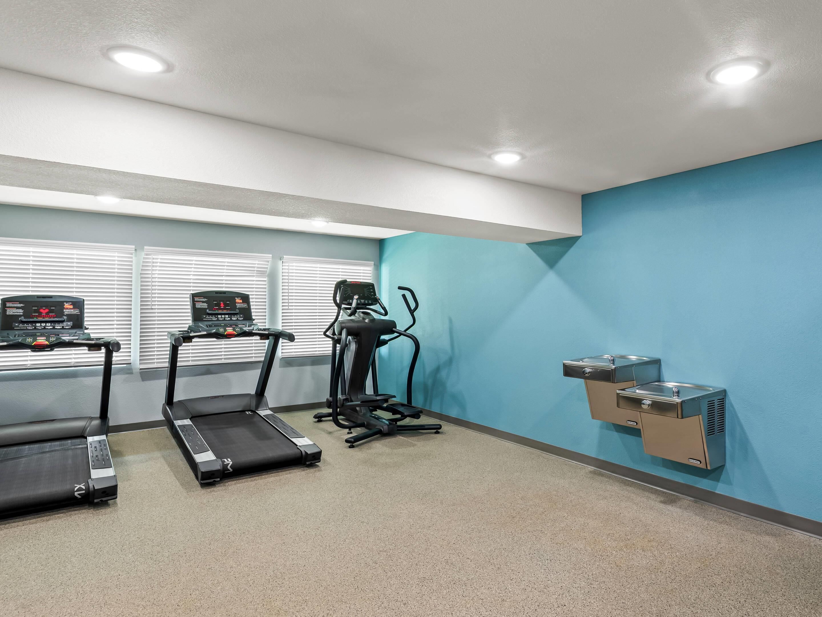 Une salle de remise en forme équipée de tapis de course, d’un vélo d’appartement et d’un climatiseur fixé au mur.