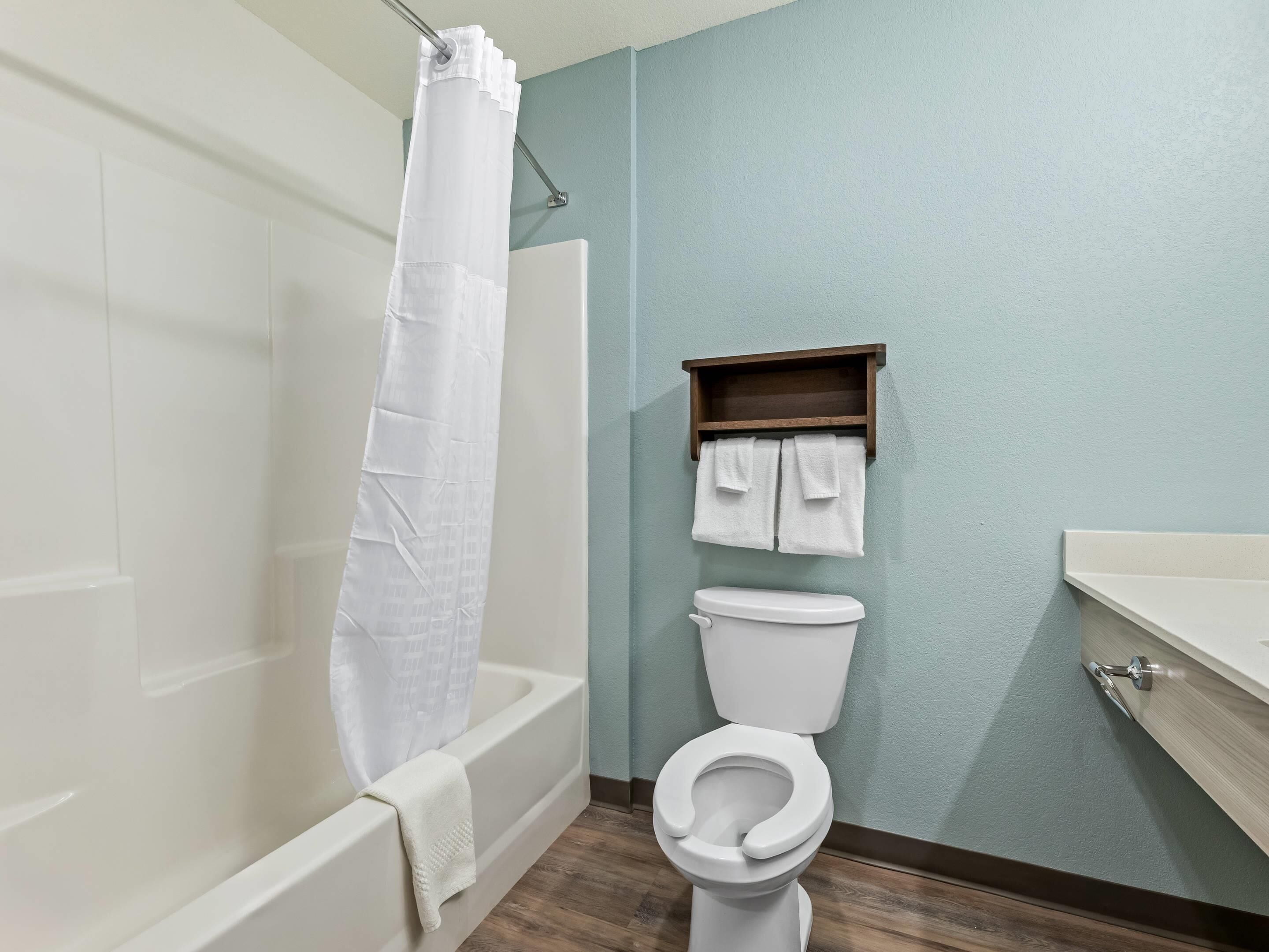 Un baño con bañera, inodoro y estante con toallas.