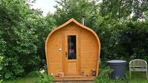 A wooden cabin with a pitched roof, a door, and a chimney. - Bee wagon with fireplace & sauna can be used all year round in the natural garden (Dargun)