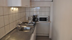 A small kitchen with a stainless steel sink, a coffee maker, and a microwave.