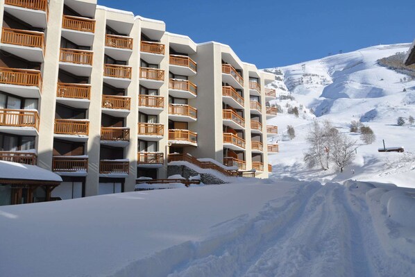 Un hotel de varios pisos con balcones, con una imponente montaña nevada de fondo.