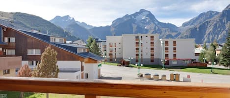 A hotel with a modern design, featuring a mix of wooden and white buildings, set against a backdrop of mountains.