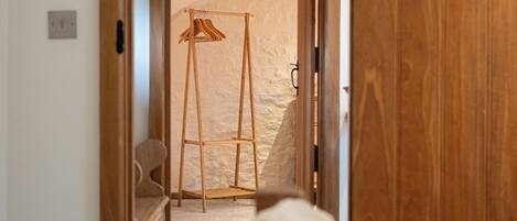 Un dormitorio con un armario de madera, una cama con cubrecama blanco y esponjoso, y una escalera de madera en la esquina.