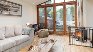 A cozy living room with a sofa, coffee table, and a fireplace. - Coach House - Lovely Home in Cheltenham (Cheltenham)