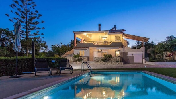 A modern house with a swimming pool, a covered patio, and a well-maintained garden.