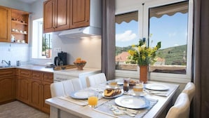 A dining area with a table set for breakfast, wooden cabinets, and a view of the countryside.