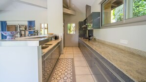 Una cocina moderna con una isla central, un ventanal con vistas a zonas verdes y una alfombra estampada en el suelo.