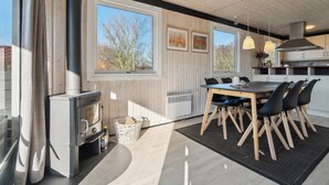 A modern kitchen with a large window, a stove, and a dining area with chairs. - Cottage near idyllic & peaceful sandy beach (Rønne)