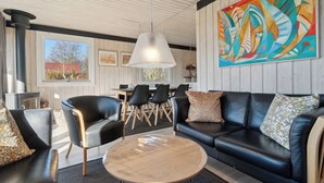A modern living room with a black leather sofa, a round wooden coffee table, and black chairs. - Cottage near idyllic & peaceful sandy beach (Rønne)