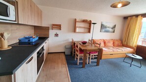 Een compacte woonruimte met een kitchenette, een eethoek en een bank.