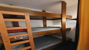 Een stapelbed met een houten trap en opbergplanken.