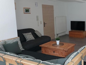 Una sala de estar con sofá, mesa de centro, televisor y radiador.
