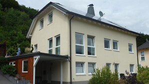 Un edificio de dos pisos con techo plano, varias ventanas y un pequeño acceso con escalones.