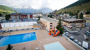 A hotel with a swimming pool, a playground, and a view of mountains.