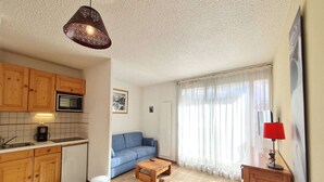 A compact living space with a kitchenette, a sofa, a coffee table, and a dining area.