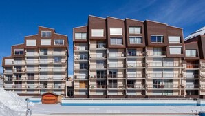 A multi-story hotel with balconies, a ski lift, and a pool area.