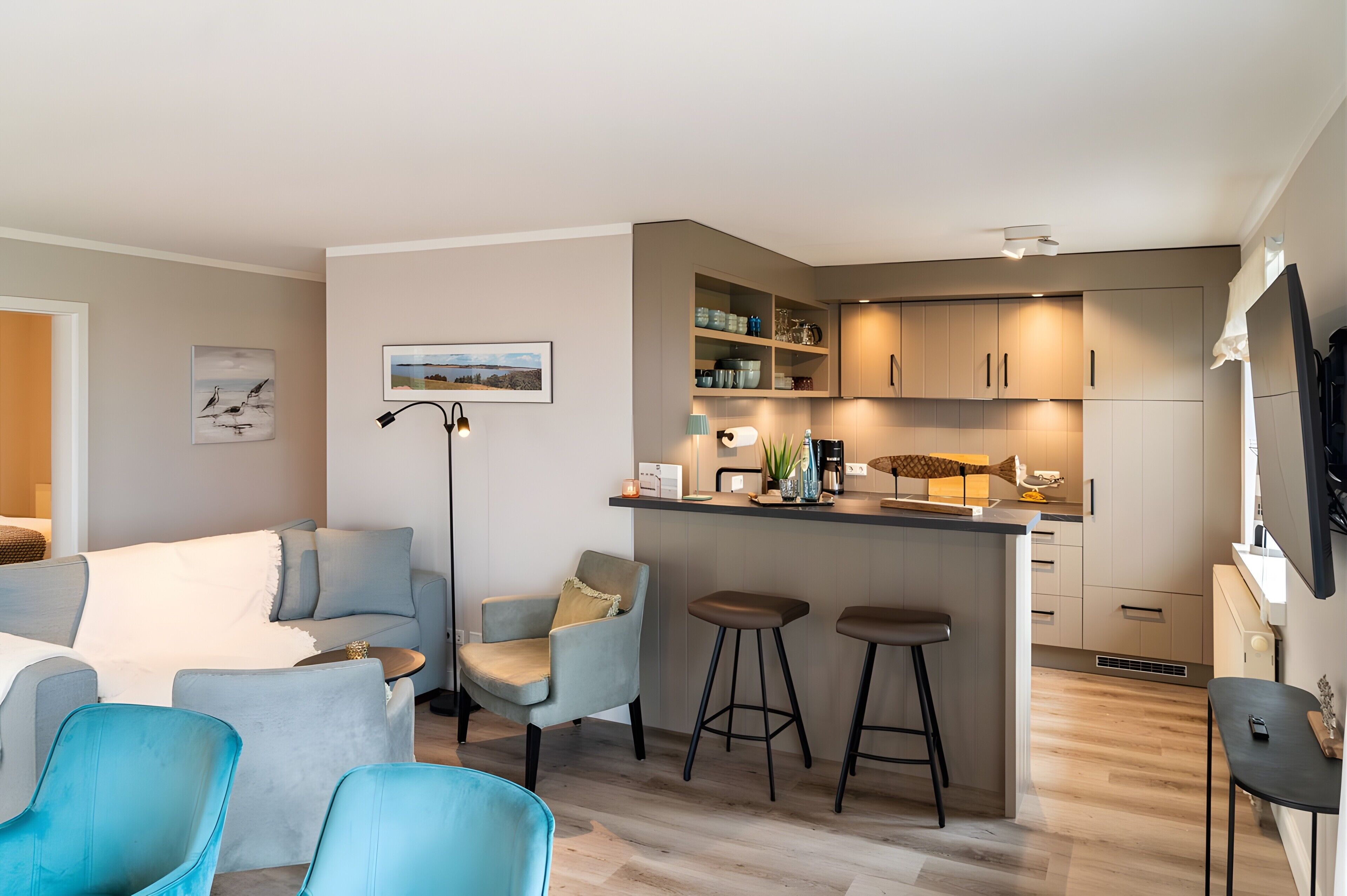 A modern kitchen with bar stools, a dining area with a sofa and chairs, and a small island with a sink.