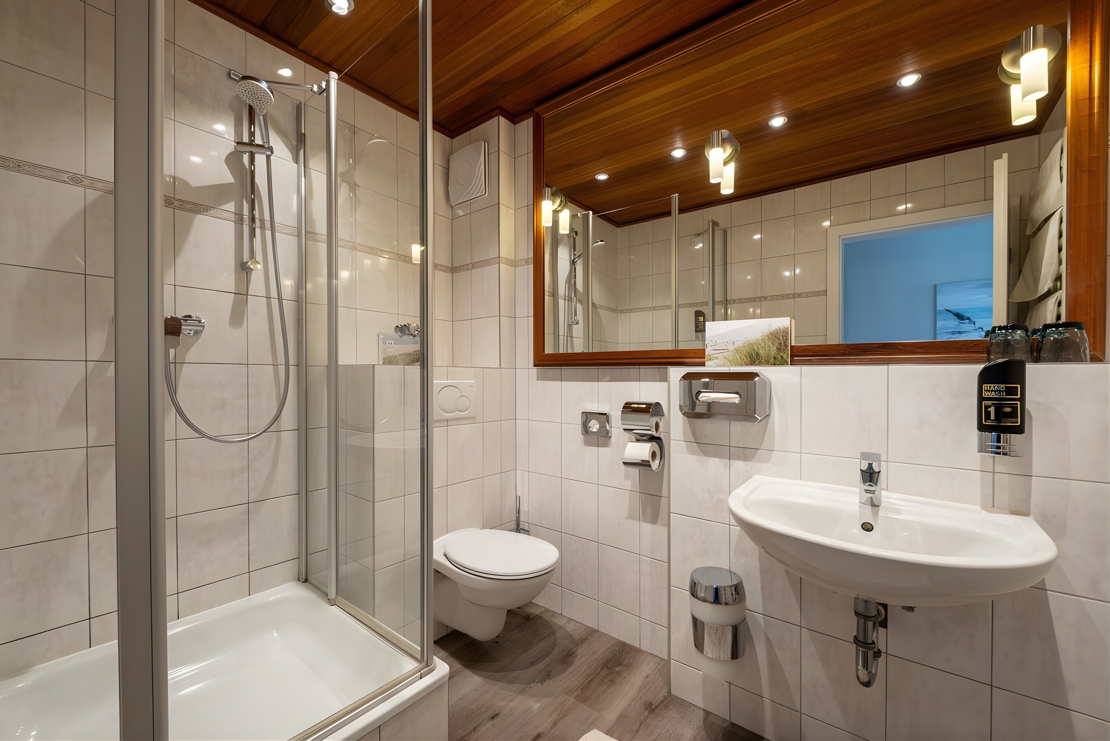 A modern bathroom with a glass-enclosed shower, a toilet, a sink, and a mirror.