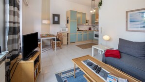 Ein modernes Wohnzimmer mit Flachbildfernseher, einer Couch, einem Couchtisch und einem Essbereich mit Tisch und Stühlen.
