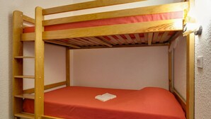Ein Stockbett mit roter Matratze und einer Leiter auf der linken Seite.