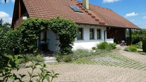 A house with a red-tiled roof, a chimney, and a garden with a paved walkway. - Apartment 'Zerlaut' with Balcony and Wi-Fi (Langenargen)