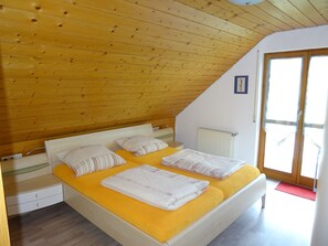 A room with a bed, a radiator, a wooden ceiling, and a door. - Apartment 'Zerlaut' with Balcony and Wi-Fi (Langenargen)