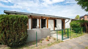 Ein modernes Einfamilienhaus mit überdachter Veranda, einem eingezäunten Garten und einer gepflasterten Auffahrt.