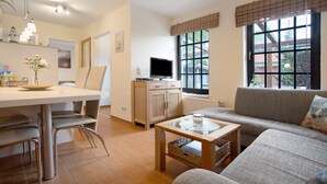Un salon moderne comprenant un canapé, une table basse, un téléviseur et un coin repas avec des chaises et une table.