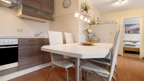 Une cuisine moderne avec une table blanche, des chaises grises et une horloge au mur.