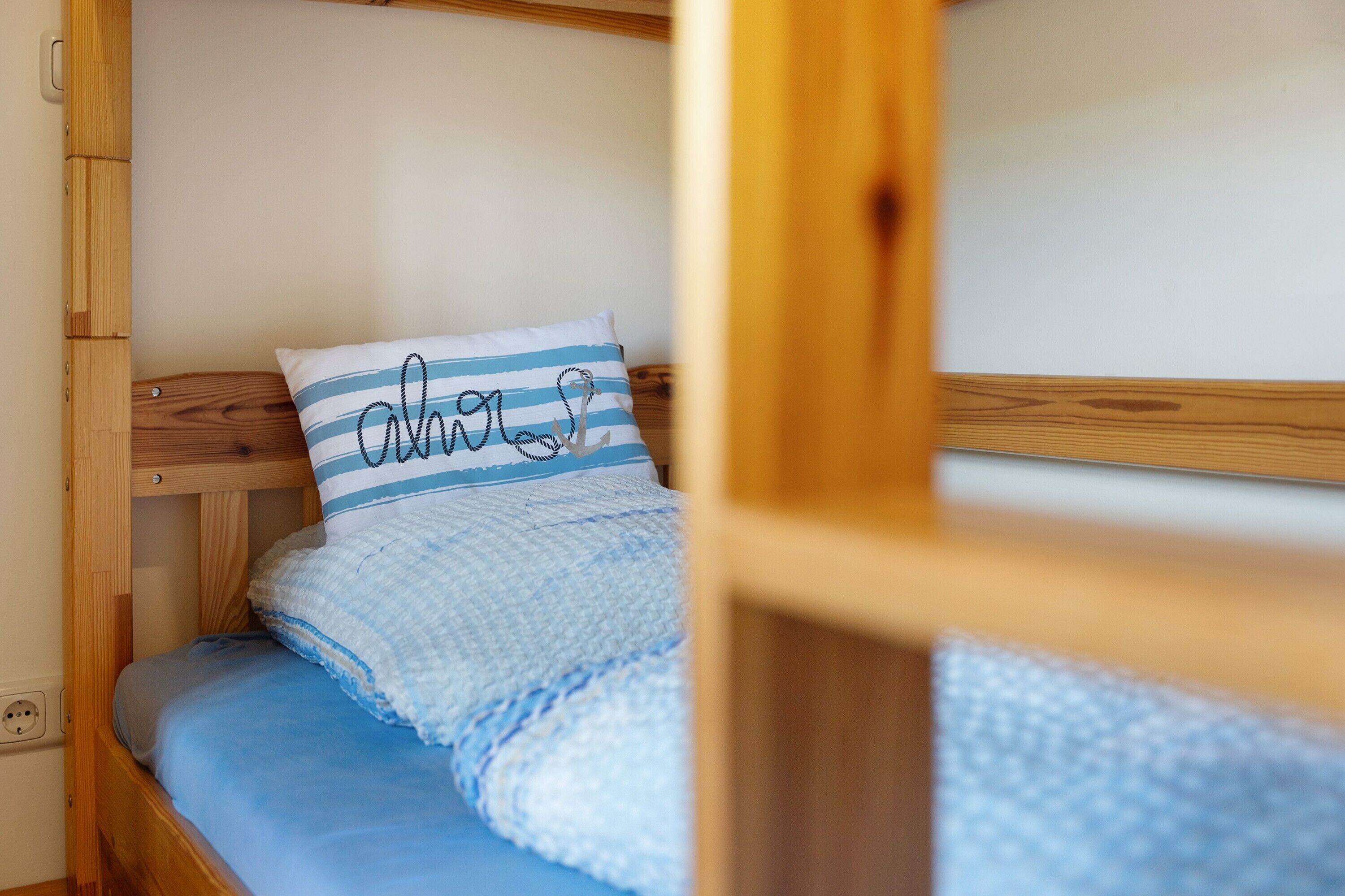 A bunk bed with a blue and white striped pillow and a blue blanket.