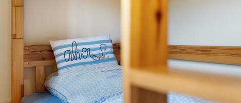 A bunk bed with a blue and white striped pillow and a blue blanket.