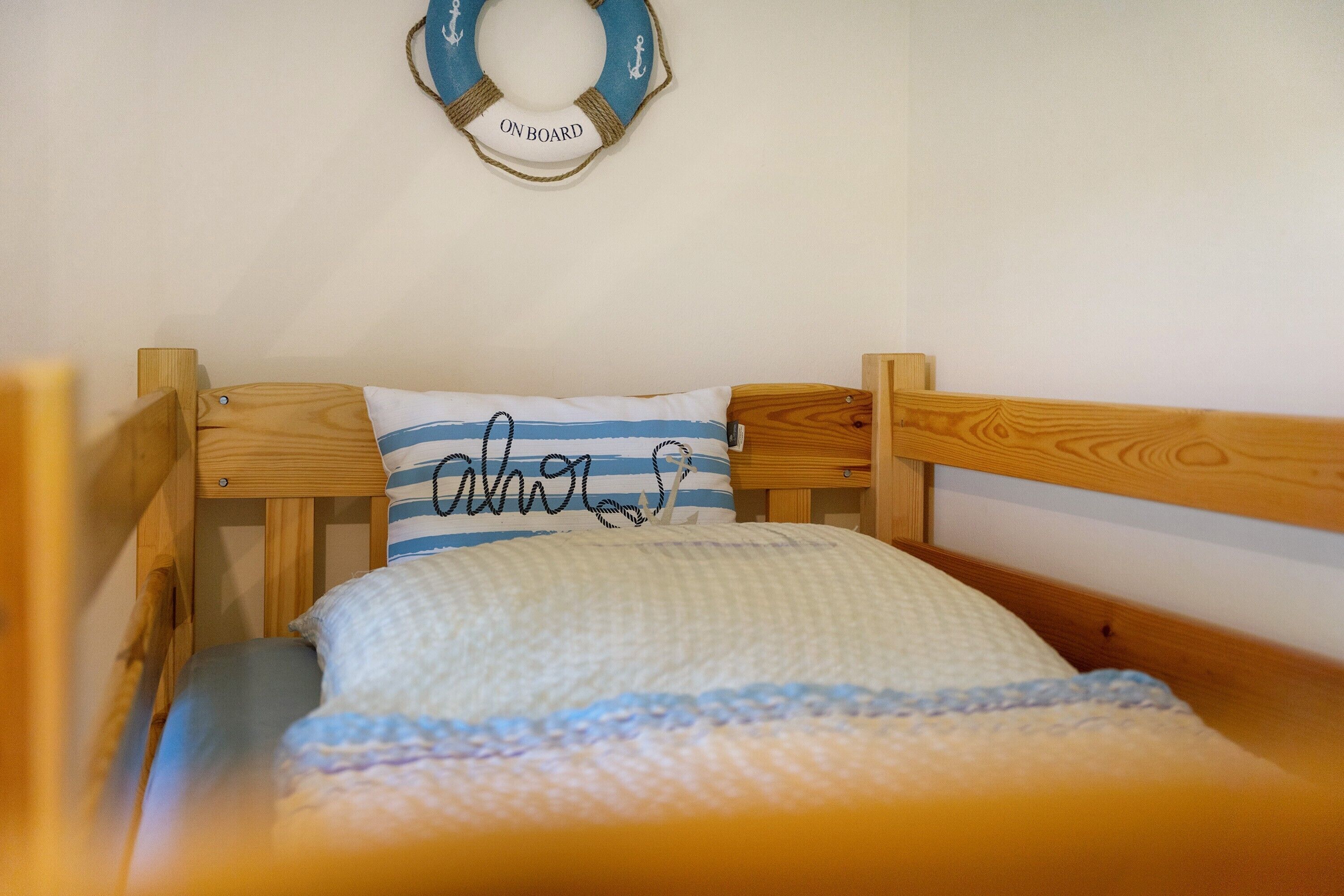 Ein Holzstockbett mit einem gestreiften Kopfkissen und einer Decke.