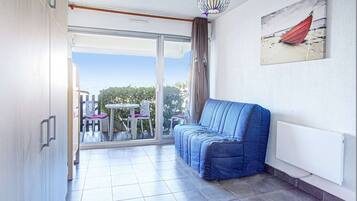 A balcony with a blue sofa, a table with chairs, and a painting on the wall.