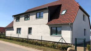 A two-story house with a red-tiled roof, multiple windows, and a fenced yard. - Apartment 'Orthsee 2' with Shared Terrace and Wi-Fi (Hohen Wangelin)