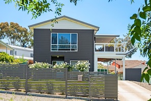 A modern two-story house with a dark exterior, large windows, and a covered front porch.