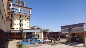 A hotel courtyard with a swimming pool, outdoor seating, and a bar area. - Soul Lounge Resort (Abuja)