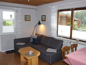 A cozy room with a sofa, a small table, a lamp, and a window with curtains.