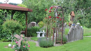 A garden with a pergola, a wooden fence, and a variety of plants and flowers.