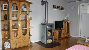 A wooden cabinet with glassware, a fireplace with a TV, and a clock on the wall.