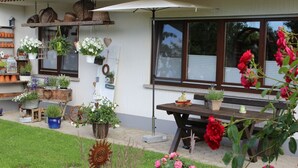 A patio area with a wooden table, potted plants, and a bench.
