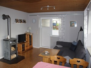 A living room with a fireplace, sofa, table, chairs, and a television.