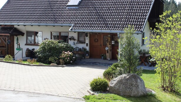 A traditional house with a tiled roof, a front porch, and a stone marker.