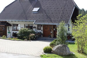 A traditional house with a tiled roof, a front porch, and a stone marker.
