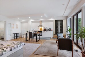 A modern, open-plan living space with a kitchen, dining area, and a large bed.