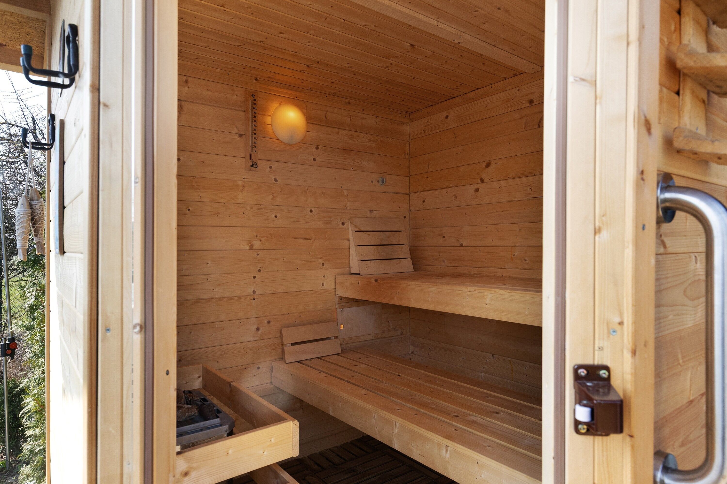 A wooden sauna with a bench, a shelf, and a light fixture.